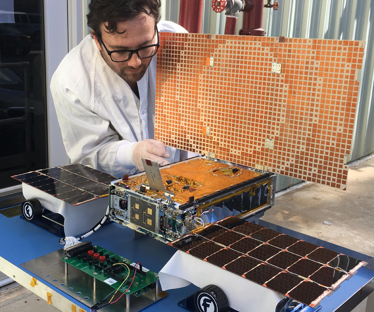 Engineer Joel Steinkraus uses sunlight to test the solar arrays on one of the Mars Cube One (MarCO) spacecraft.