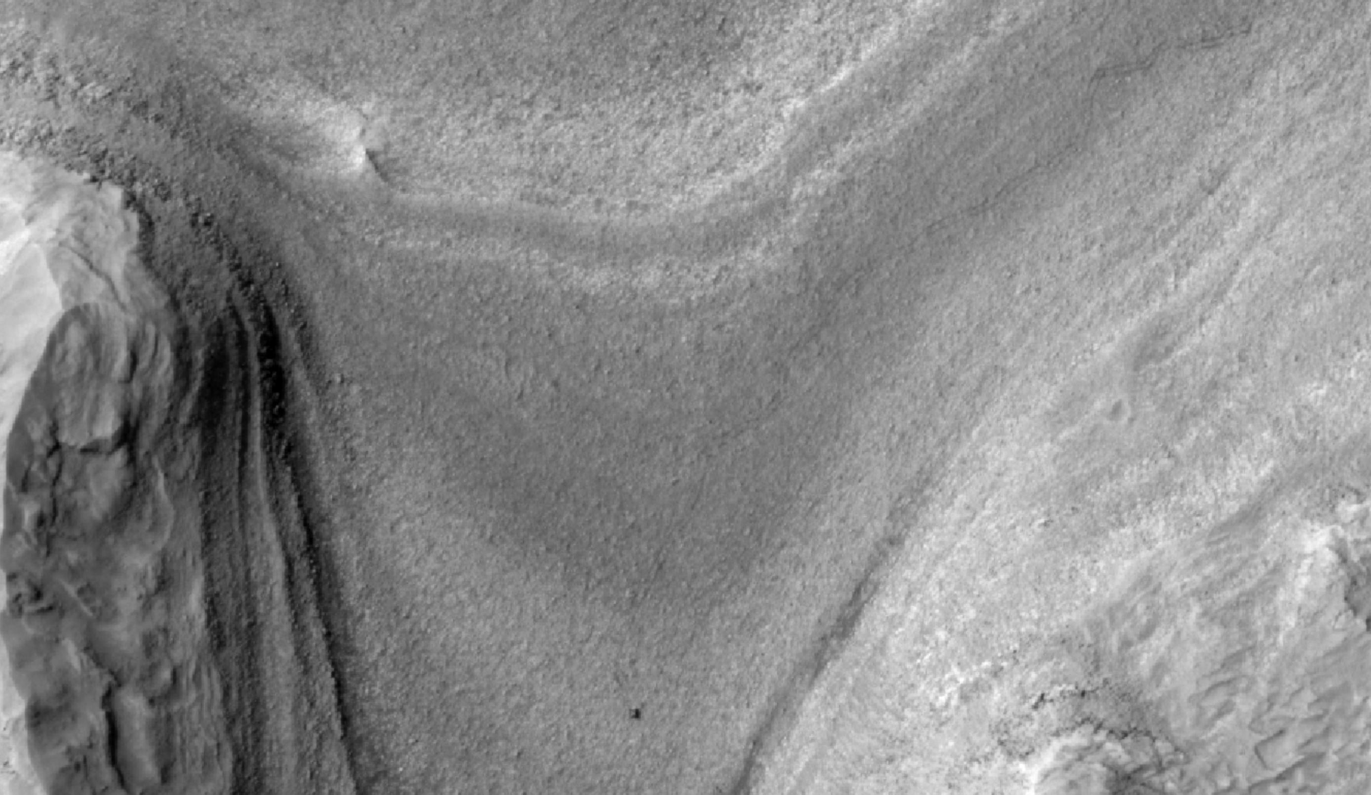 NASAs Curiosity rover appears as a dark speck in this view captured on Feb. 28, 2025, by the HiRISE camera aboard NASAs Mars Reconnaissance Orbiter.