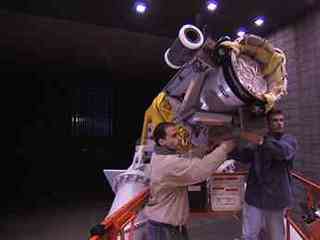 This image shows two engineers aiming the cannon that will fire the tightly packed parachute into the wind tunnel.