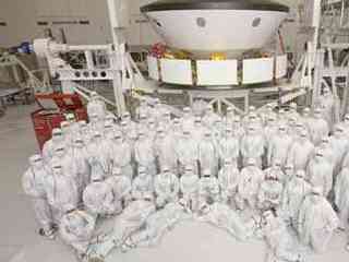 This photo shows 70 members of the Mars Science Laboratory team in Jet Propulsion Laboratory's Spacecraft Assembly Facility after they have prepared the spacecraft to go to a different area for the environmental tests.  The team members are dressed in "bunny suits" (white protective gear) and are positioned in various poses in front of the spacecraft.