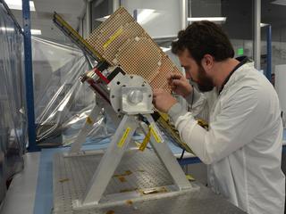 Joel Steinkraus, lead mechanical engineer for the MarCO (Mars Cube One) CubeSat spacecraft, adjusts a model of one of the two spacecraft.
