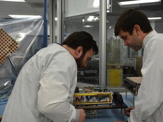 Engineers for NASA's MarCO (Mars Cube One) technology demonstration inspect one of the two MarCO CubeSats. Joel Steinkraus, MarCO lead mechanical engineer, left, and Andy Klesh, MarCO chief engineer, are on the team at NASA's Jet Propulsion Laboratory, Pasadena, California, preparing twin MarCO CubeSats.