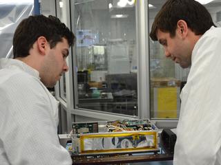 Engineers for NASA's MarCO (Mars Cube One) technology demonstration inspect one of the two MarCO CubeSats. Cody Colley, MarCO integration and test deputy, left, and Andy Klesh, MarCO chief engineer, are on the team at NASA's Jet Propulsion Laboratory, Pasadena, California, preparing twin MarCO CubeSats.