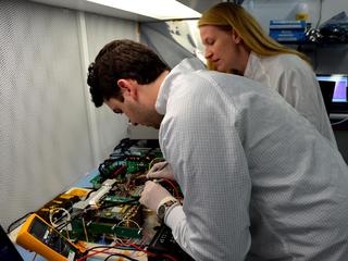 Engineers for NASA's MarCO (Mars Cube One) technology demonstration inspect the MarCO test bed, which contains components that are identical to those built for a flight to Mars. Cody Colley, left, MarCO integration and test deputy, and Shannon Statham, MarCO integration and test lead, are on the team at NASA's Jet Propulsion Laboratory, Pasadena, California, preparing twin MarCO CubeSats.