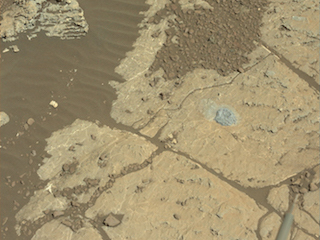 Rock surface with small drill hole and pile of drill tailings.
