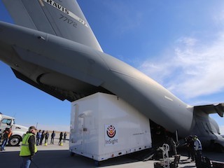 large crate being loaded into military transport plane