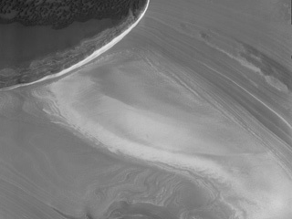 This image from NASA's 2001 Mars Odyssey spacecraft shows part of the margin of the north polar cap and the surrounding plains. The layering of the ice is easily visible due to the dust that is deposited on the top of the ice every year, creating layering over millions of years.