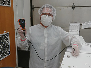 JPL mechanical technician Eddie Castro uses a paint meter to measure the paint thickness on the Mars 2020 rover chassis.