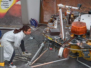 Engineer Marleen Sundgaard watches as the robotic arm on a test version of NASA's Mars InSight lander grasps a model of the spacecraft's seismometer. This work was done at NASA's Jet Propulsion Laboratory in Pasadena, California.