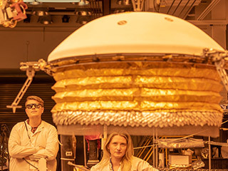 ForeSight, a fully functional, full-size model of NASA's InSight lander, practices deploying a model of the lander's Wind and Thermal Shield while engineers Phil Bailey (left) and Jaime Singer (center) look on. The Wind and Thermal Shield protects InSight's seismometer. This testing was done at NASA's Jet Propulsion Laboratory in Pasadena, California.