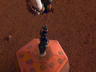The seismometer is the copper-colored object in this image, which was taken around Martian dusk.