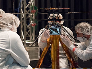 NASA Mars Helicopter team members work the flight model (the vehicle going to Mars) in the Space Simulator.