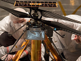 Members of the NASA Mars Helicopter team inspect the flight model (the actual vehicle going to the Red Planet), inside the Space Simulator.