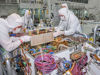 Technicians at JPL integrate the rover motor controller assembly (RMCA) into the Mars 2020 rover's body