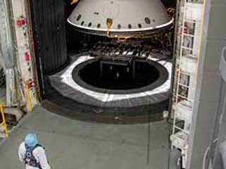 An engineer inspects the completed spacecraft that will carry NASA's next Mars rover to the Red Planet, prior to a test in the Space Simulator Facility at NASA's Jet Propulsion Laboratory in Pasadena, California.