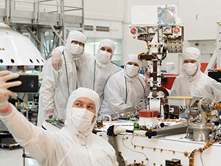 ​​Members of NASA's Mars 2020 project take a moment after attaching the remote sensing mast to the Mars 2020 rover.