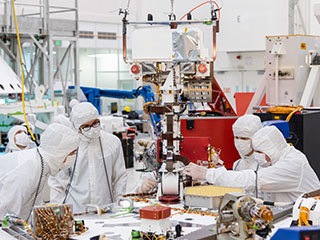 Engineers and technicians at NASA's Jet Propulsion Laboratory in Pasadena, California, install the remote sensing mast on the Mars 2020 rover.