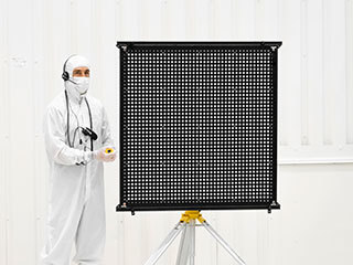 Engineer Chris Chatellier stands next to a target board with 1,600 dots. The board was one of several used on July 23, 2019, in the Spacecraft Assembly Facility's High Bay 1 at NASA's Jet Propulsion Laboratory in Pasadena, California, to calibrate the forward-facing cameras on the Mars 2020 rover.