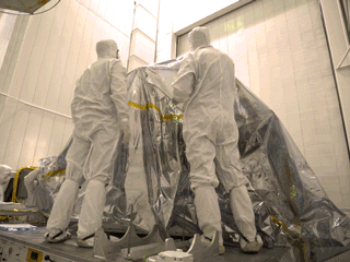 In time-lapse video bunny-suited engineers remove the inner layer of protective foil on NASA's Mars 2020 rover after it was moved to a different building at JPL for testing.