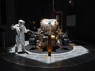 An engineer working on NASA's Mars 2020 mission uses a solar intensity probe to measure and compare the amount of artificial sunlight that reaches different portions of the rover.
