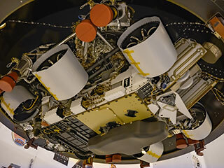 Seen from below, NASA's Mars 2020 Perseverance rover bears a plaque to the right of its middle wheel.