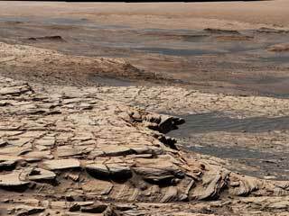 Curiosity Mars rover captured this view from "Greenheugh Pediment." In the foreground is the pediment's sandstone cap. At center is the "clay-bearing unit"; the floor of Gale Crater is in the distance.