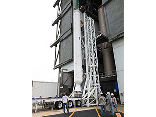 A crane is attached to the second of four solid rocket boosters for the Atlas V rocket at KSC