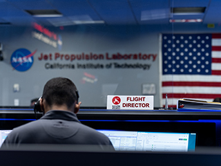 Flight director sign in mission control with American flag in background