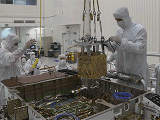 NASA Technicians the MOXIE instrument into the belly of the Perseverance rover