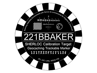 A round coin with a striped border, with letters and symbols to assist in adjusting the SHERLOC instrument. 