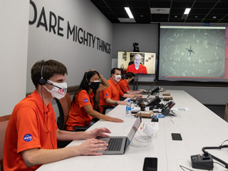 Members of NASA’s Ingenuity helicopter team react to data showing that the helicopter completed its first flight