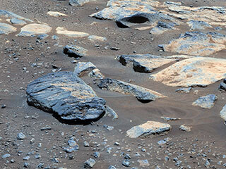 This is a colored image of large boulders on the sandy surface of Mars.