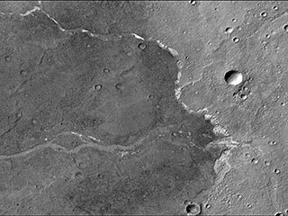 NASA’s Mars Reconnaissance Orbiter used its Context Camera to capture this image of Bosporos Planum, a location on Mars. The white specks are salt deposits found within a dry channel. The largest impact crater in the scene is nearly 1 mile (1.5 kilometers) across.