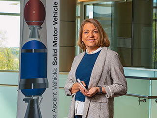 Angie Jackman, manager of the Mars Ascent Vehicle (MAV) project, holds a 3D-printed model of the tubes NASA’s Perseverance rover is already filling with Martian rock and soil samples. 