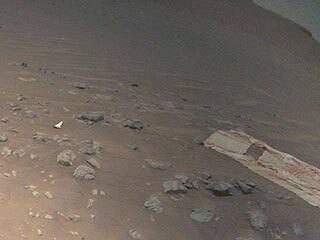 Perseverance’s backshell, supersonic parachute, and associated debris field is strewn across the Martian surface in this image captured by NASA’s Ingenuity Mars Helicopter during its 26th flight on April 19, 2022.