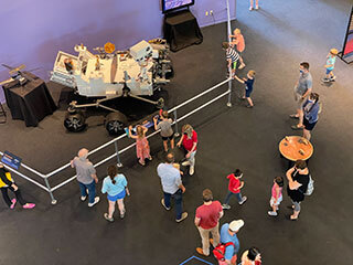 Overhead view of members of the public looking at a life-size model of NASA's Perseverance rover at the Science Center of Iowa.