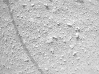 A small piece of foreign object debris (FOD) is seen in footage from the navigation camera of NASA's Ingenuity Mars Helicopter during its 33rd flight on Mars on Sept 24, 2022. The FOD is seen attached to one of the rotorcraft's landing legs, then drifting away.