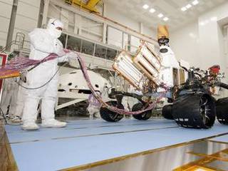 A test operator in clean-room garb holds umbilical cables for NASA's Mars rover Curiosity during the rover's first drive test, on July 23, 2010.
