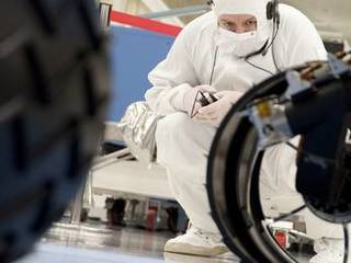 A test operator in clean-room garb observes rolling of the wheels during the first drive test of NASA's Curiosity rover, on July 23, 2010.