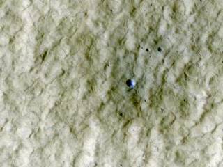 At the center of this view of an area of mid-latitude northern Mars, a fresh crater about 6 meters (20 feet) in diameter holds an exposure of bright material, blue in this false-color image.