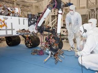 Test operators in a clean room at NASA's Jet Propulsion Laboratory, Pasadena, Calif., monitor some of the first motions by the robotic arm on the Mars rover Curiosity after installation in August 2010. This photo, taken Aug. 31, 2010, shows the arm in a partially extended position. The arm has a reach of about 2.3 meters (7.5 feet) from the front of the rover body.