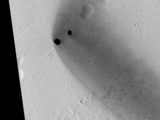 Two dark, rimless pits are located to the northwest of Ascraeus Mons in the Tharsis volcanic region of Mars.