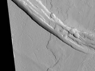 This image shows a graben (a trough formed when the ground drops between two parallel faults) and a lava flow in the Tharsis volcanic province of Mars. North is up.