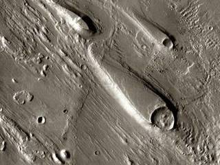 In Ares Vallis, teardrop mesas extend like pennants behind impact craters, where the raised rocky rims diverted the floods and protected the ground from erosion.