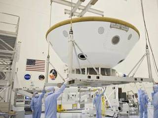 At the Payload Hazardous Servicing Facility at NASA's Kennedy Space Center in Florida, technicians using an overhead crane, move the aeroshell, a component of NASA's Mars Science Laboratory (MSL), back to a work stand after a spin and balance test.