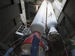 Inside the Vertical Integration Facility at Space Launch Complex 41 on Cape Canaveral Air Force Station in Florida, technicians using an overhead crane guide the final solid rocket motor into position for mating to the first stage of a United Launch Alliance Atlas V rocket.