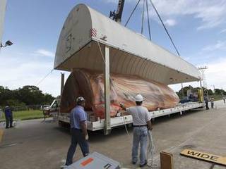 At the Payload Hazardous Servicing Facility at NASA's Kennedy Space Center in Florida, workers uncover half of the Atlas V payload fairing for NASA's Mars Science Laboratory (MSL) mission, encased in plastic, on its transportation pallet.