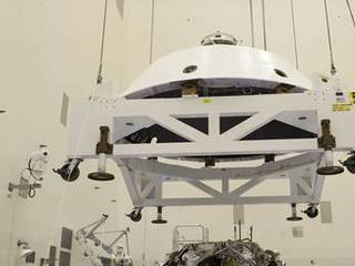 In the Payload Hazardous Servicing Facility at NASA's Kennedy Space Center in Florida, technicians guide the backshell as it is lowered over NASA's Mars Science Laboratory (MSL) rover, Curiosity, for encapsulation.