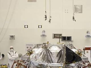 At the Payload Hazardous Servicing Facility at NASA's Kennedy Space Center in Florida, an overhead crane is being lowered over a rocket-powered descent stage for integration with NASA's Mars Science Laboratory (MSL) rover, known as Curiosity.