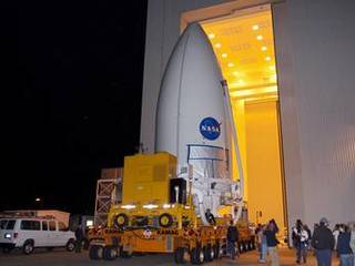 Standing atop a payload transporter, the Atlas V rocket payload fairing containing NASA's Mars Science Laboratory (MSL) spacecraft rolls out of the Payload Hazardous Servicing Facility at Kennedy Space Center in Florida, beginning the move to Space Launch Complex 41.